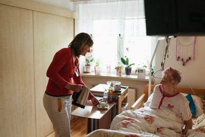 Caregiver serving tea to a senior woman