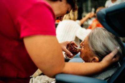 Caregiver helping an elderly person drink tea