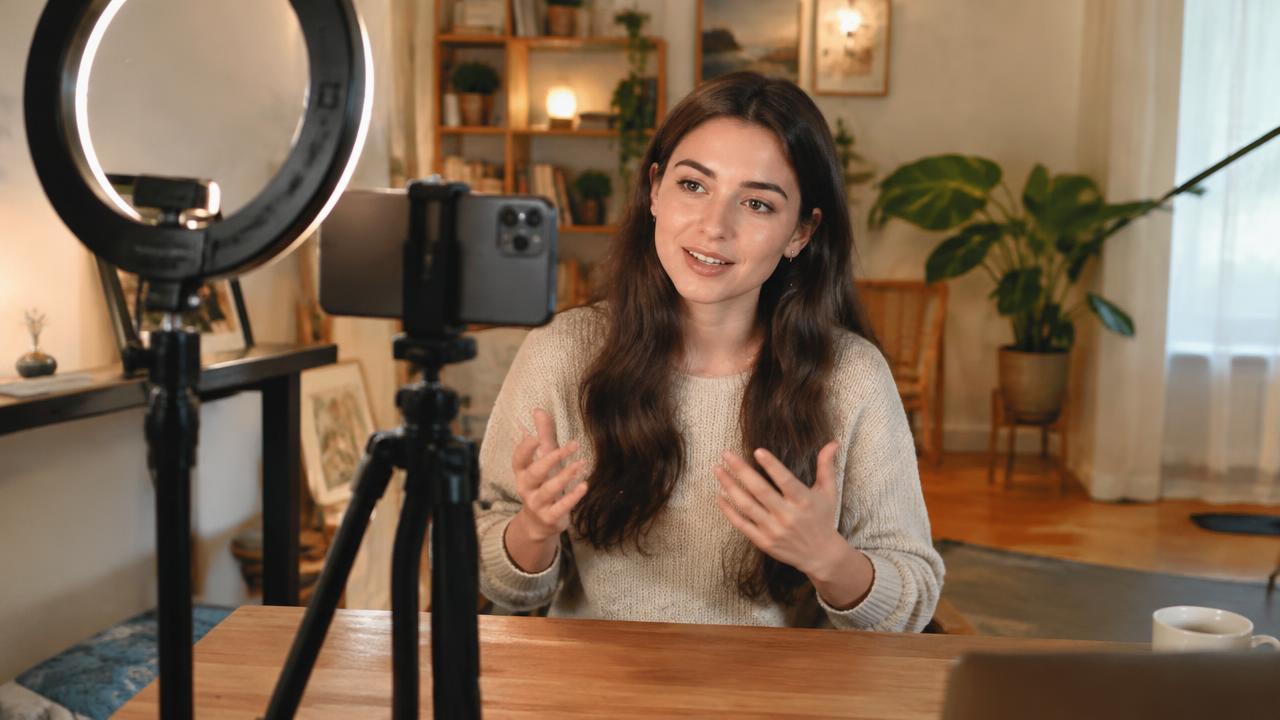 A creator filming a social media video on her phone with a ring light at home.